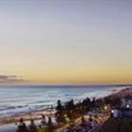 A coastal hotel with a view of the ocean and a sunset.