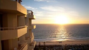 A high-rise building with a balcony overlooking a beach at sunset. - Rendezvous Hotel Perth Scarborough (Scarborough)