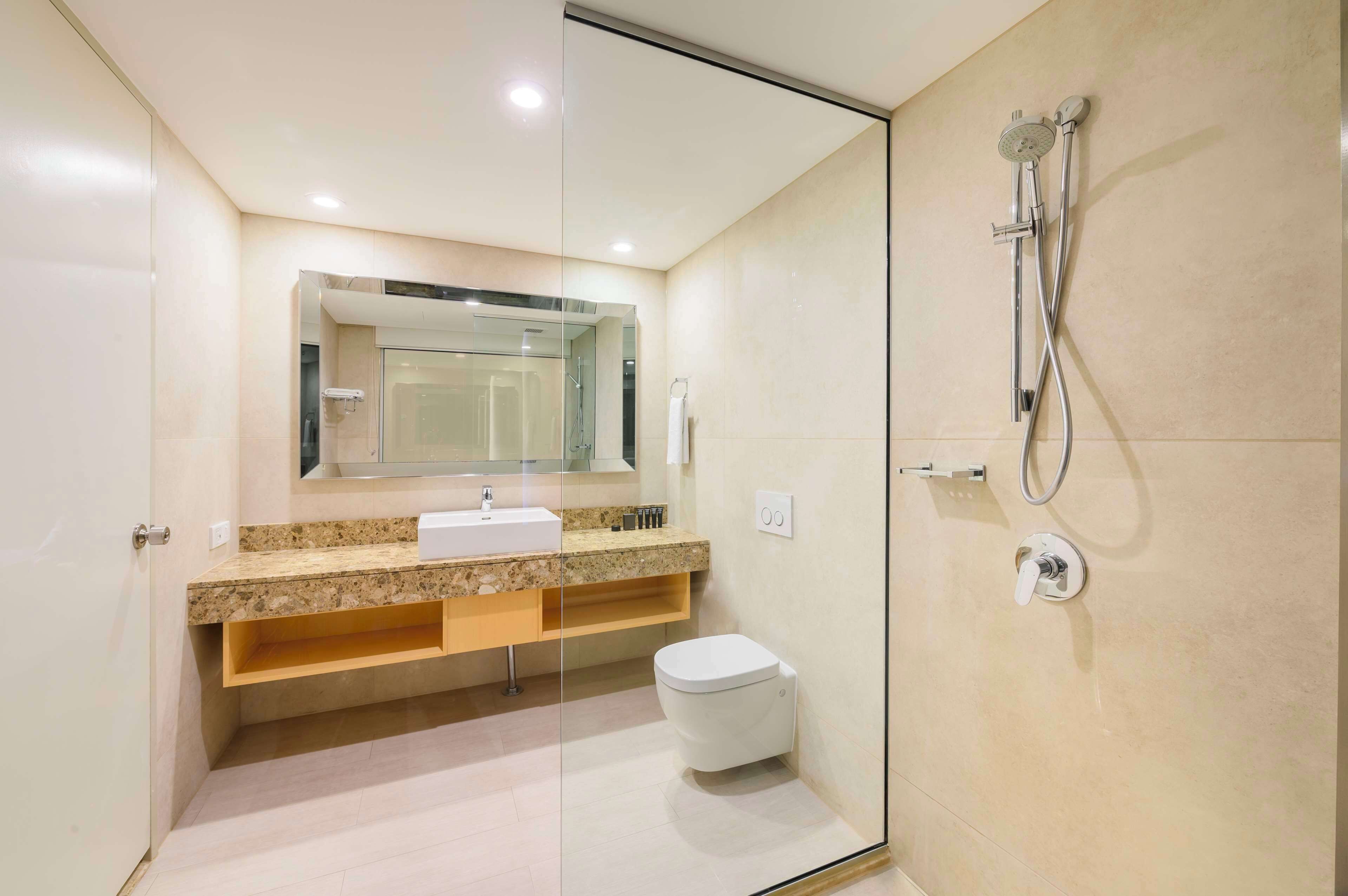 A modern bathroom with a glass-enclosed shower, a sink with a marble countertop, and a toilet.