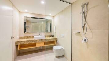 A modern bathroom with a glass-enclosed shower, a sink with a marble countertop, and a toilet.