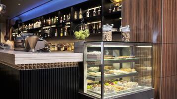 A bakery display case with various pastries and a hanging basket of apples.