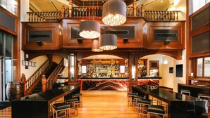 Eine Bar mit einer Marmorplatte, verschiedenen Sitzgelegenheiten und einer Treppe zu einer oberen Ebene.