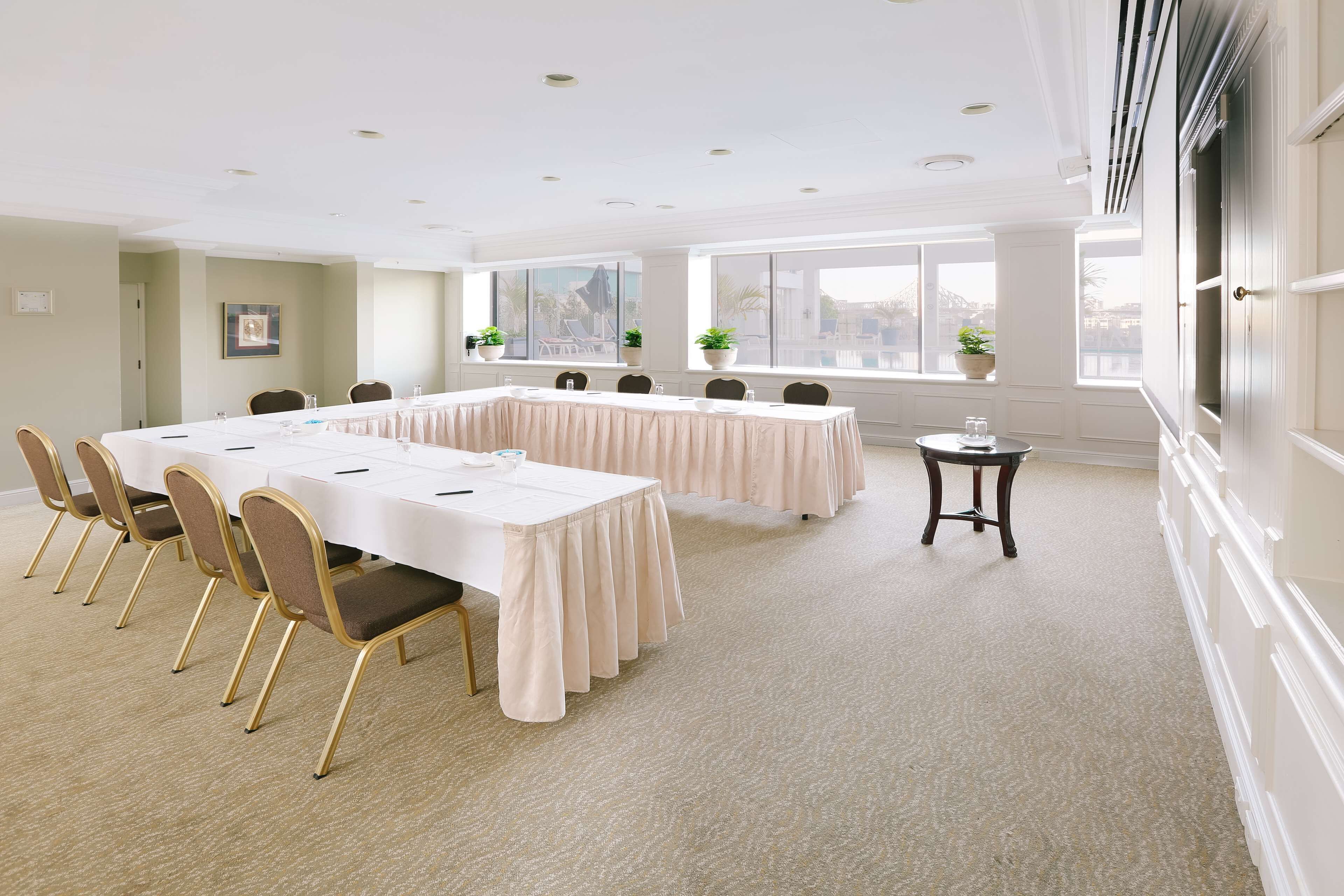 A conference room with a long table, chairs, and potted plants.