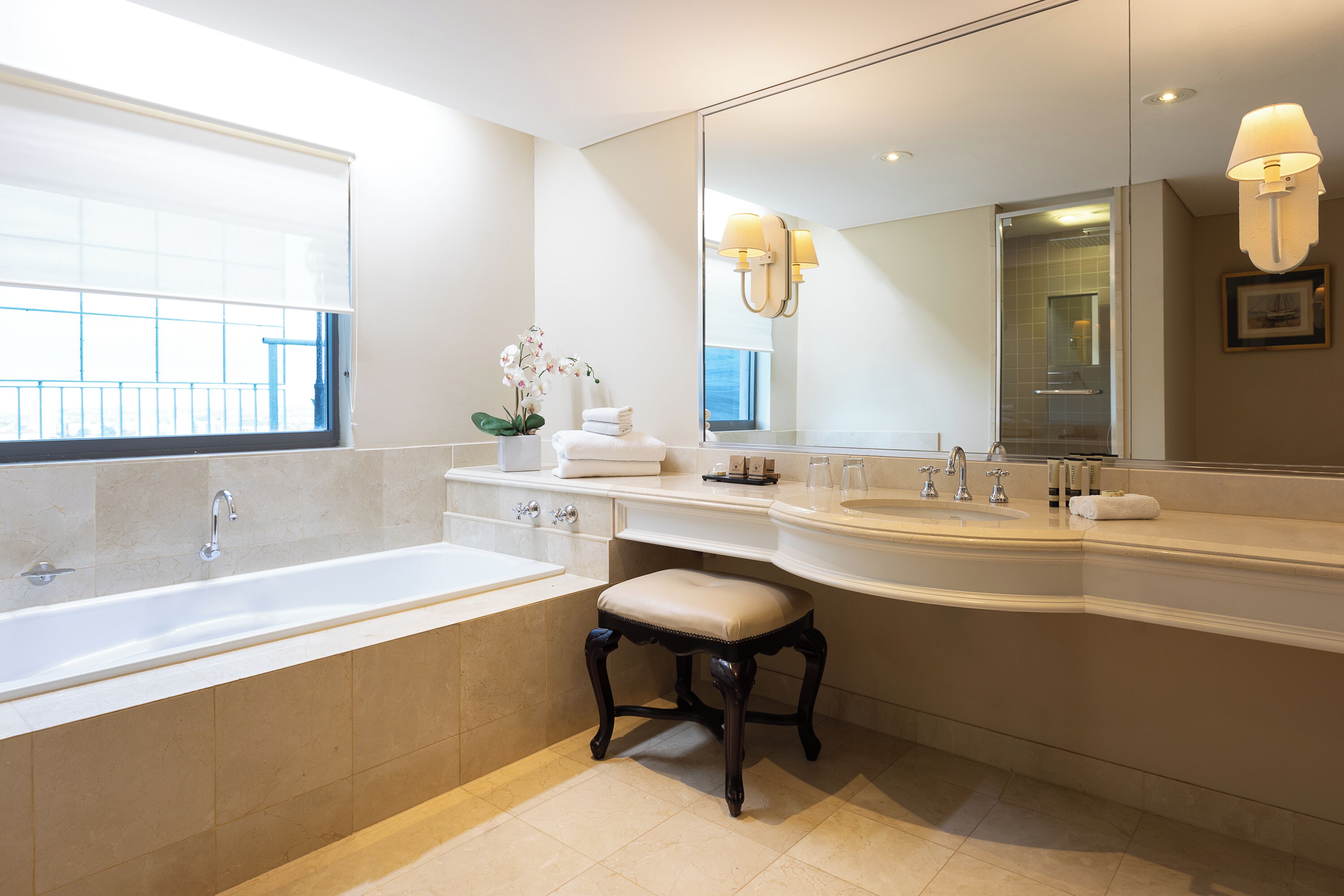 A modern bathroom with a large bathtub, two sinks, a vanity, and a large mirror.