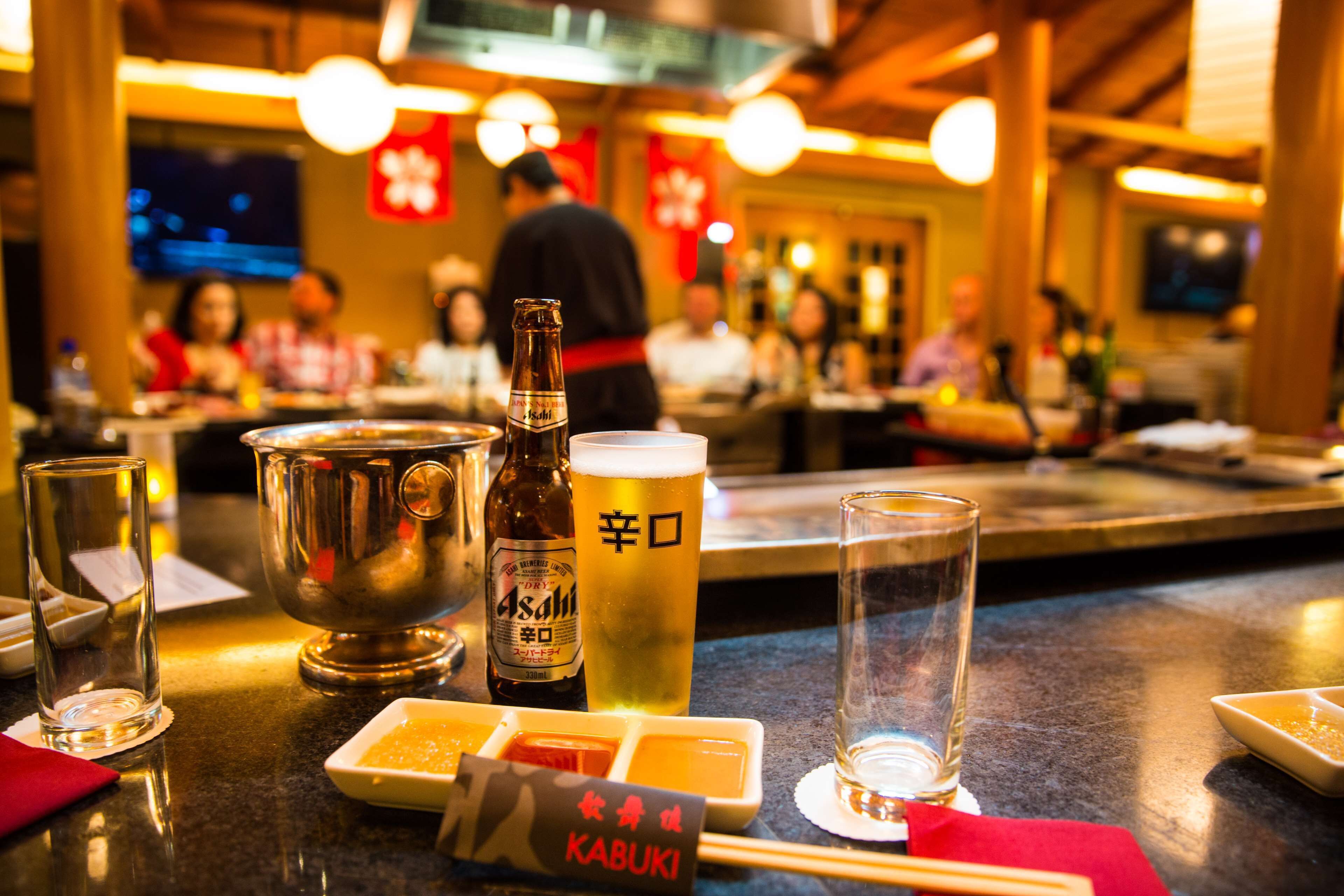 A bar area with a beer bottle, glasses, and a menu.