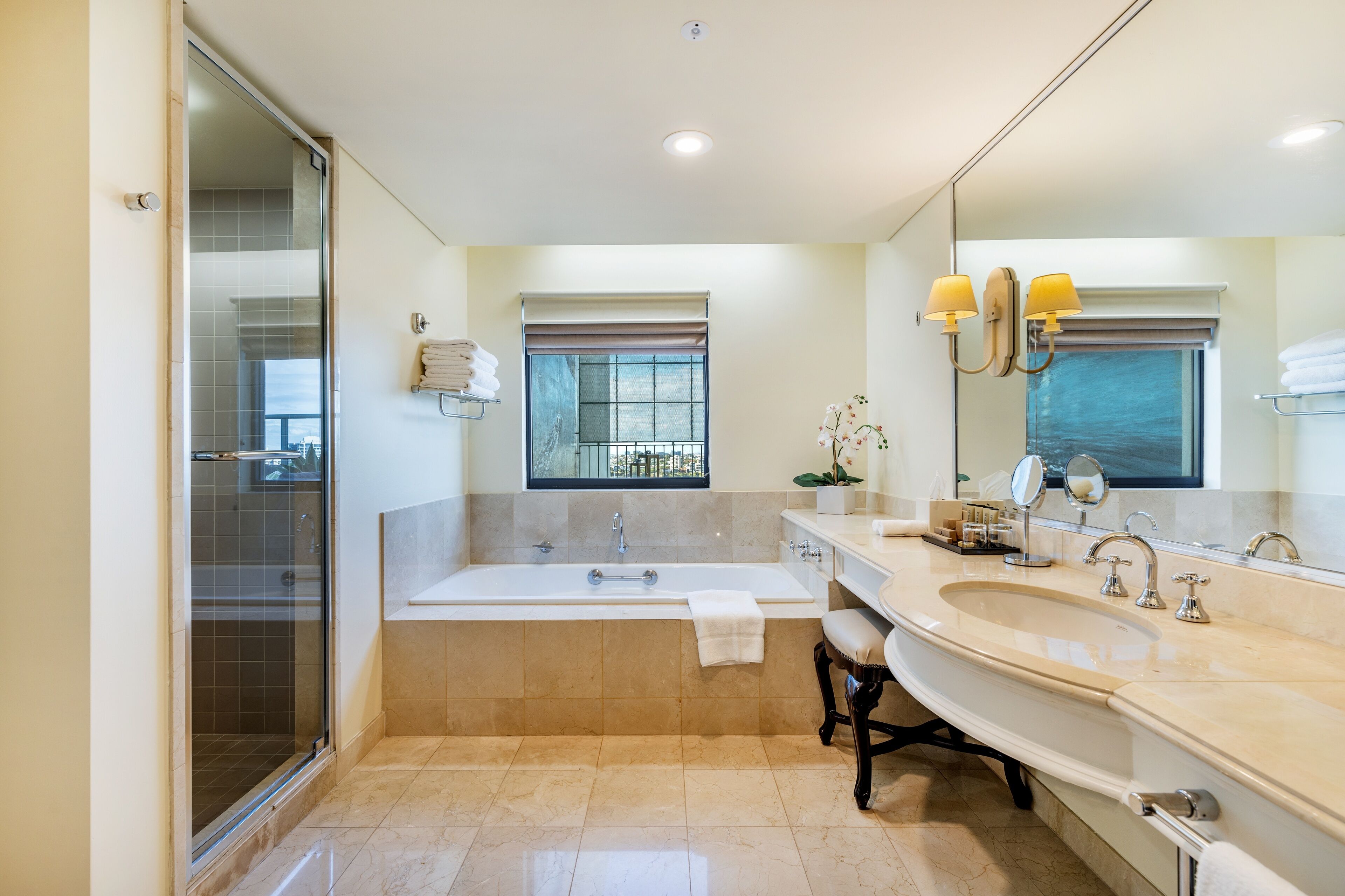 A modern bathroom with a glass-enclosed shower, a freestanding bathtub, and a double sink vanity.