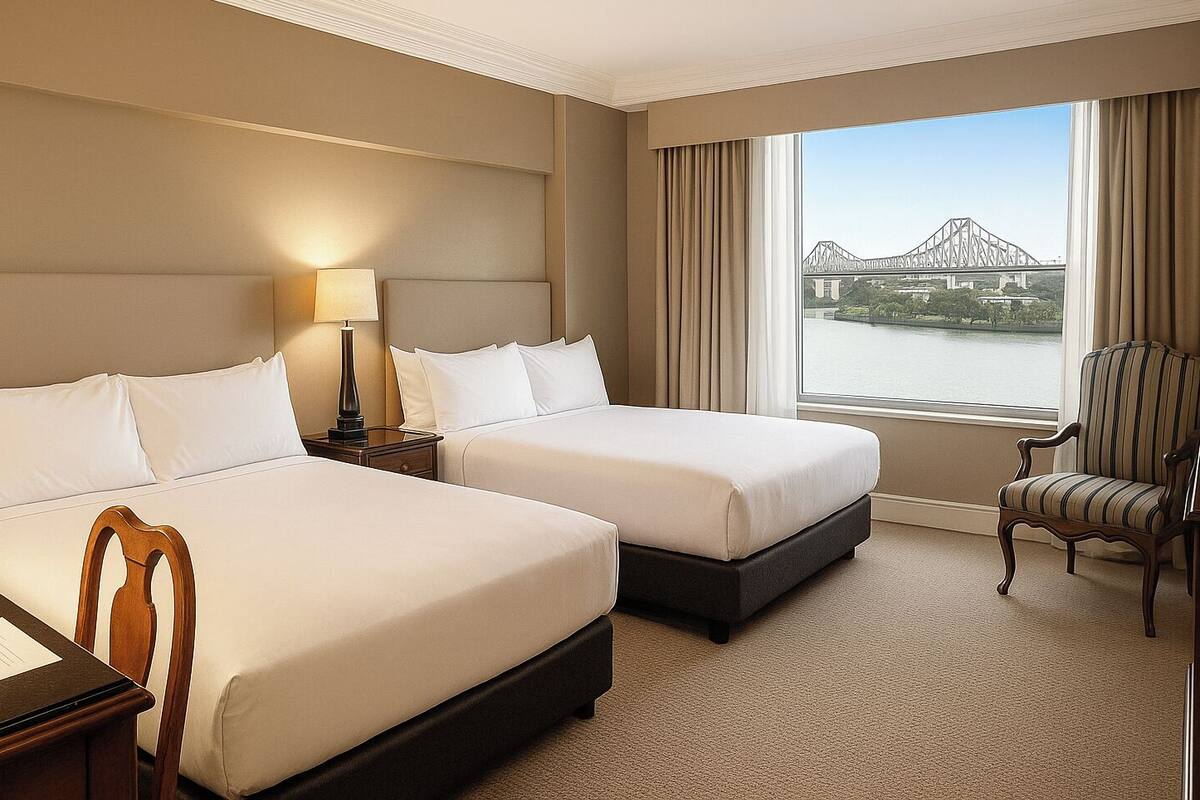 Een hotelkamer met twee bedden, een nachtkastje met een lamp, een stoel en een groot raam met uitzicht op een brug.