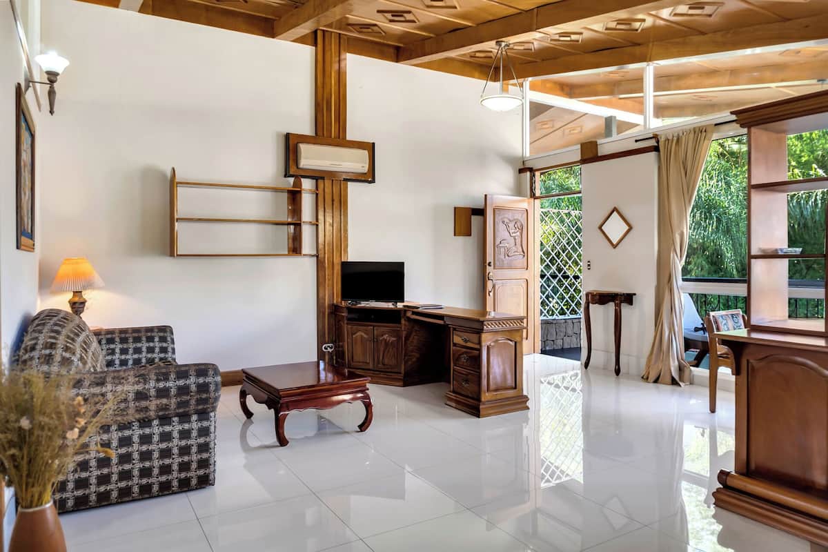 A living room with a sofa, TV, wooden cabinet, and a dining area with a table and chairs.