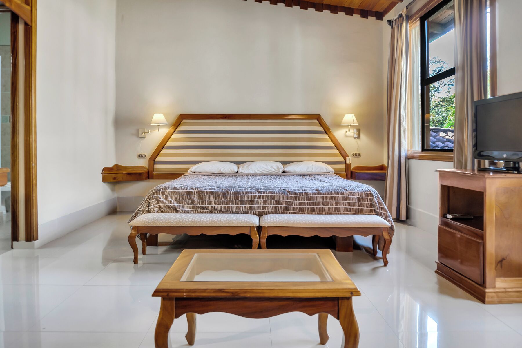 Une chambre à coucher avec un lit, des lampes de chevet, une télévision et une armoire en bois.