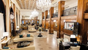 A spacious lobby with a grand chandelier, elegant furniture, and a large television screen. - The Lord Nelson Hotel & Suites (Halifax)