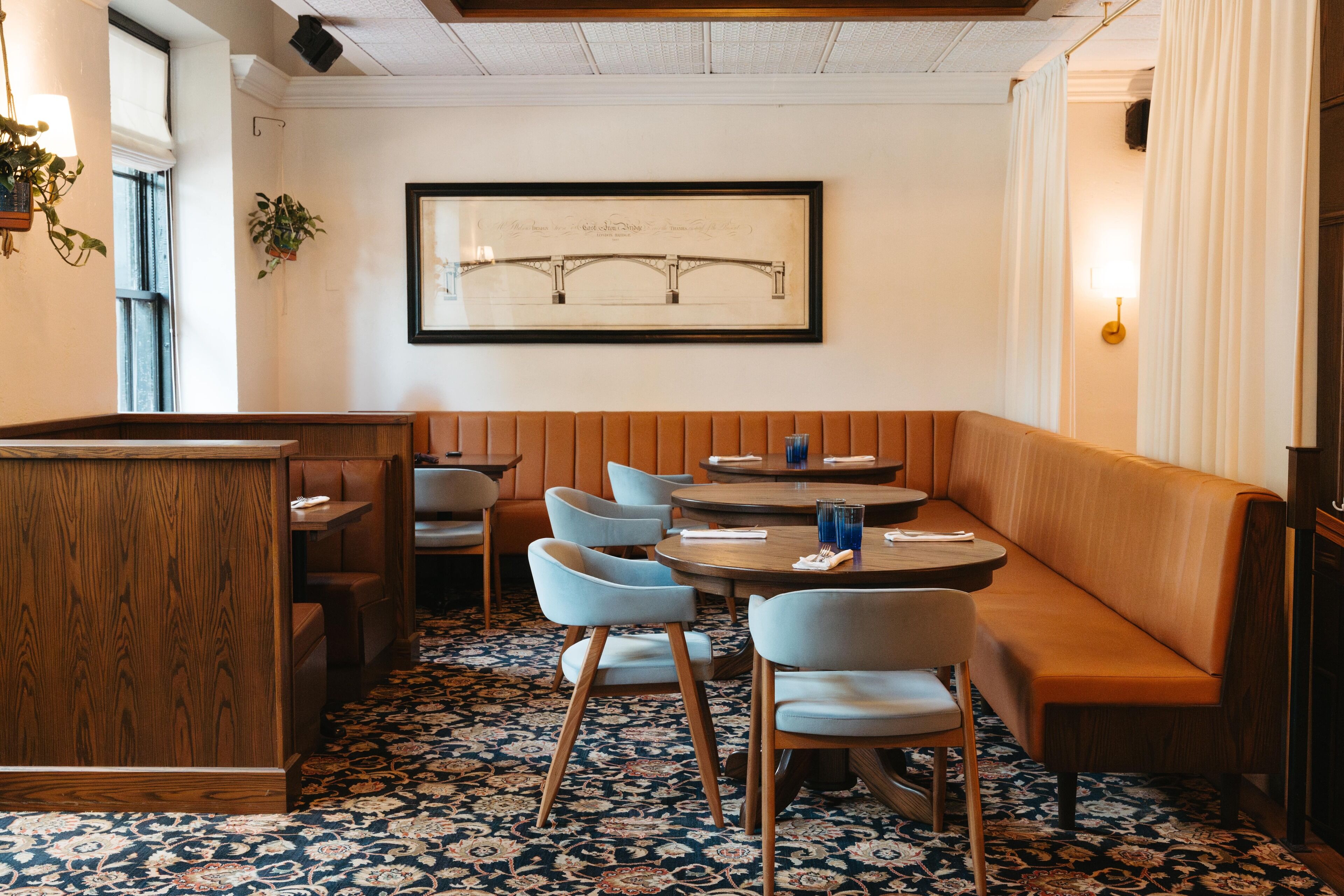 Un restaurante con una zona de estar con bancos de madera, una mesa redonda y un suelo con estampado.