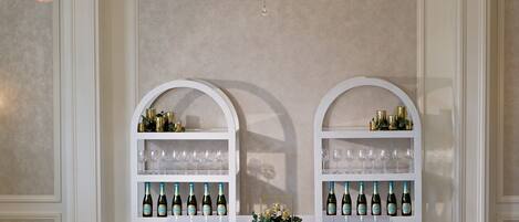 Un comedor formal con candelabro, un aparador blanco con botellas de vino y sillas elegantes.