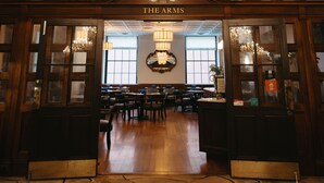 A grand lobby with a chandelier, wooden doors labeled "The Arms," and a seating area with tables and chairs. - The Lord Nelson Hotel & Suites (Halifax)