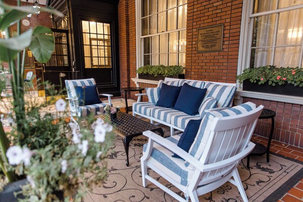 A cozy outdoor seating area with a brick wall, two white striped sofas, and a small table.