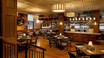 A restaurant with wooden interiors, multiple dining tables, and hanging pendant lights.