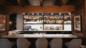 A bar area with a marble countertop, multiple shelves of liquor bottles, and bar stools. - The Lord Nelson Hotel & Suites (Halifax)