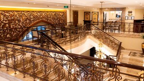 A grand hotel lobby with ornate iron railings, a marble staircase, and a chandelier. - Sheraton Khalidiya Hotel (Abu Dhabi)