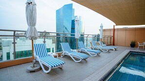 A rooftop pool area with lounge chairs and umbrellas, overlooking a cityscape with modern buildings. - Sheraton Khalidiya Hotel (Abu Dhabi)