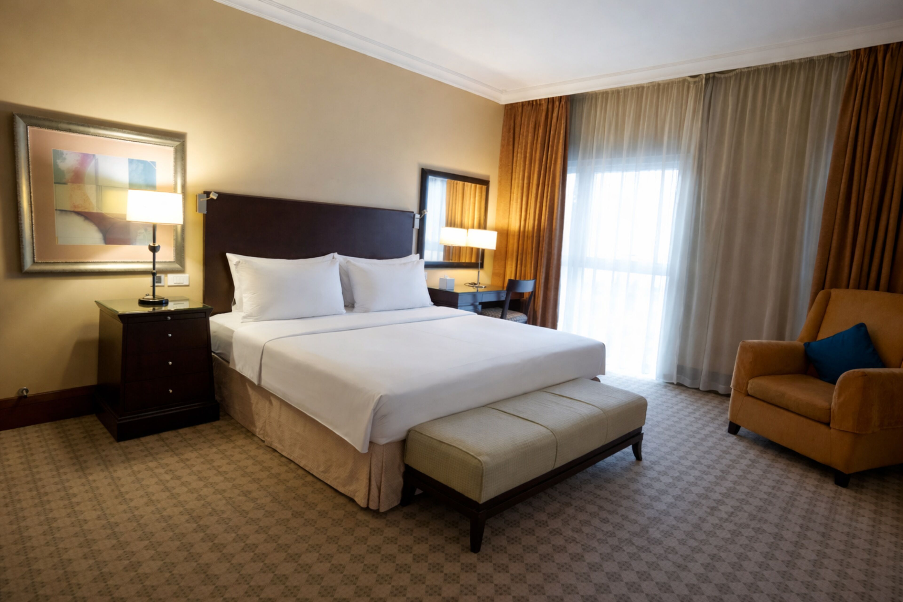 A hotel room with a large bed, a bedside table, a chair, and a window with curtains.