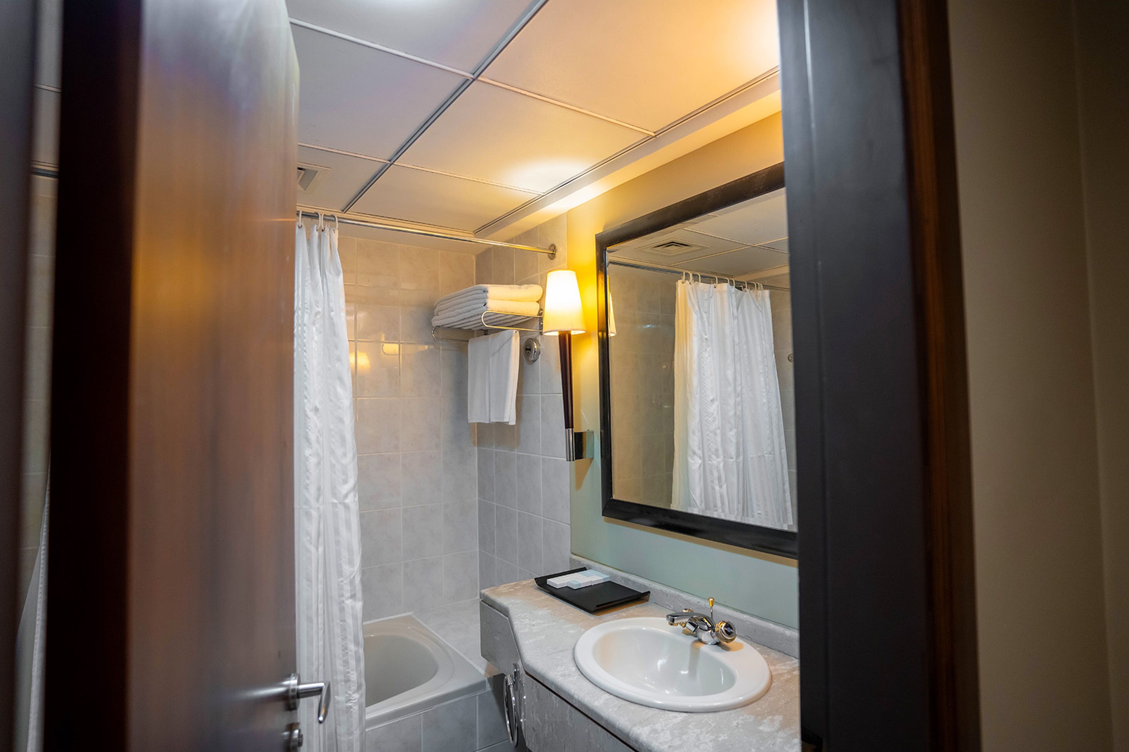 A bathroom with a bathtub, a sink, a mirror, and a towel rack.