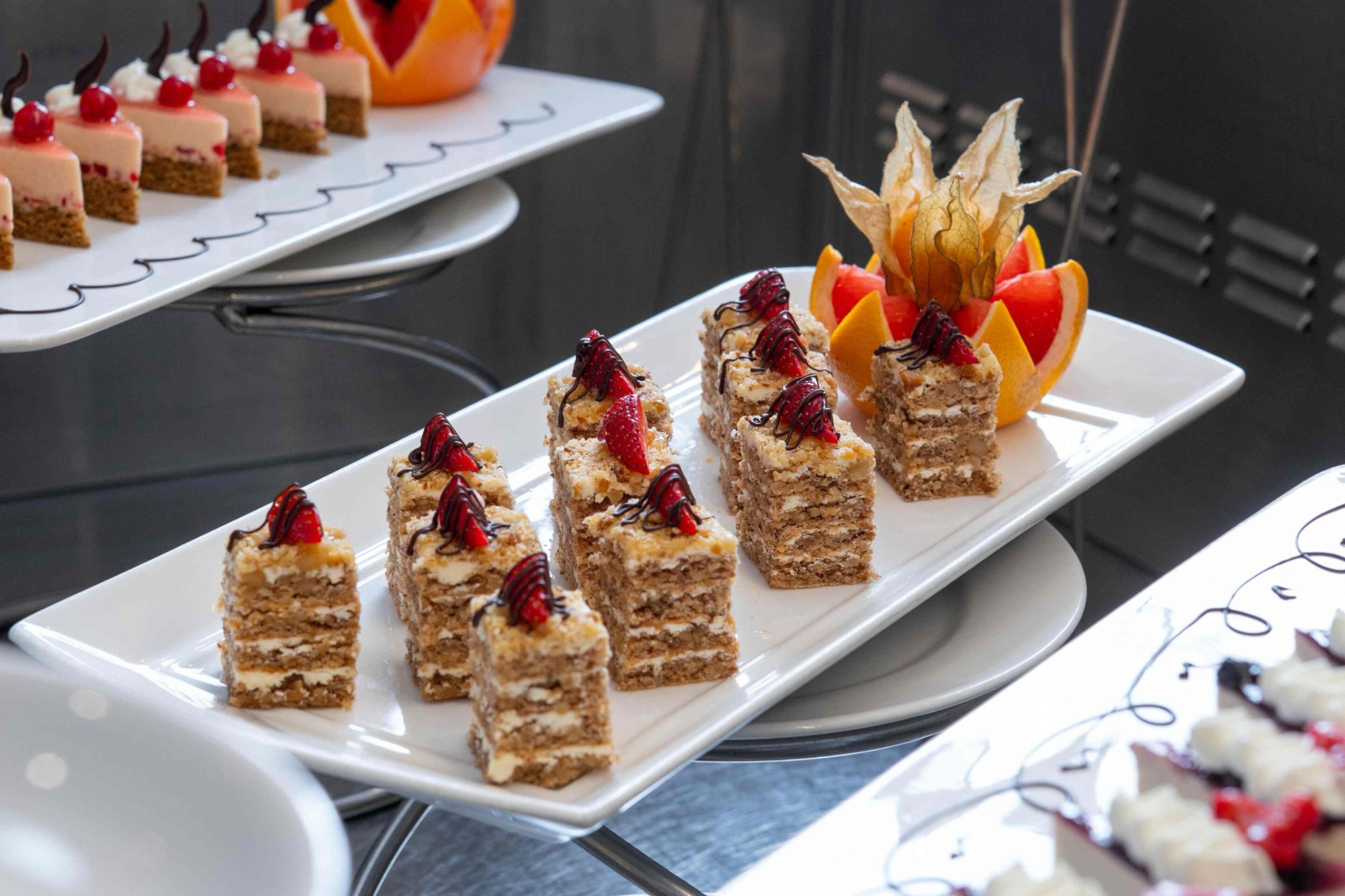 A variety of desserts on white rectangular plates, arranged on a table.