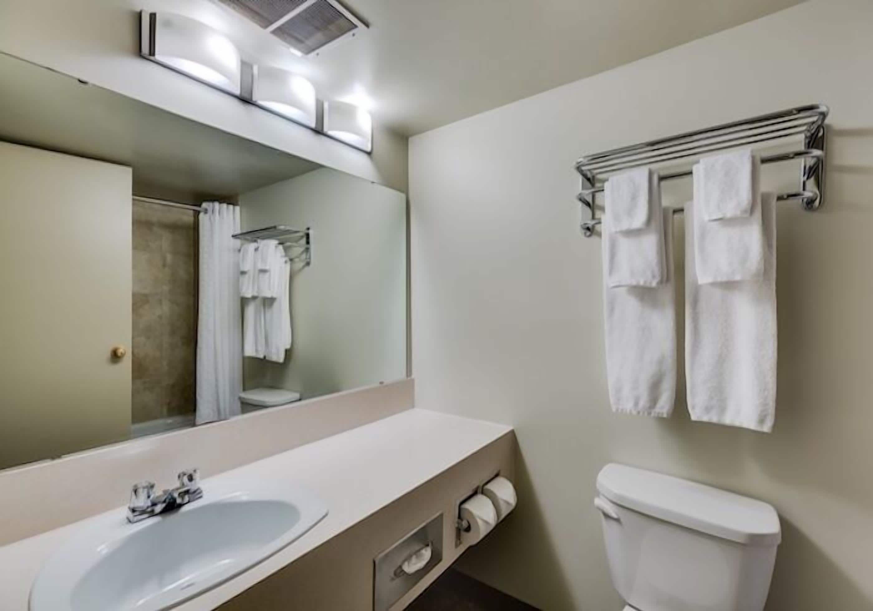 Un baño con lavabo, espejo, toallero y retrete.
