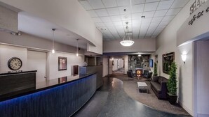 A hotel reception area with a curved reception desk, a clock, and a fireplace in the background.