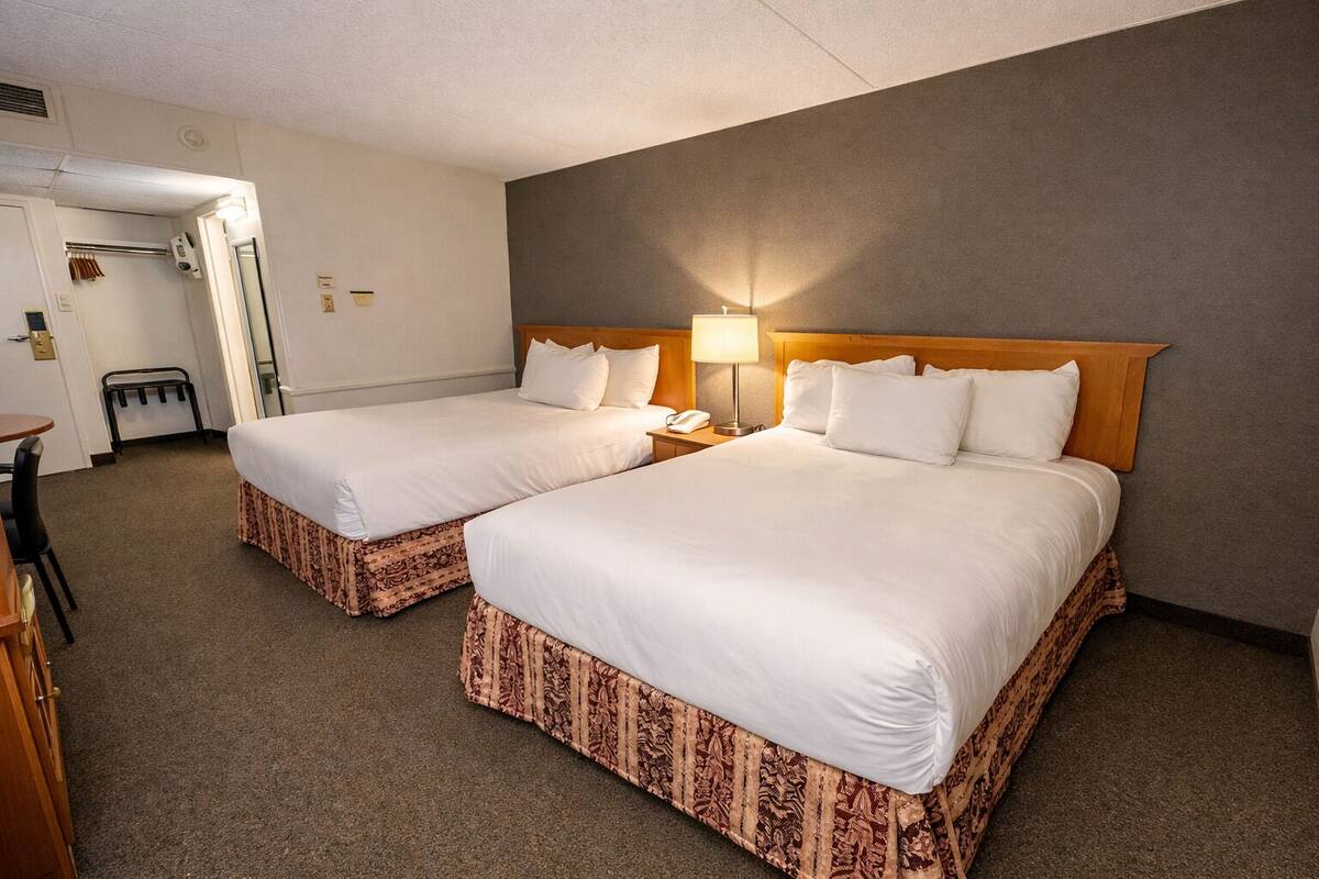 Une chambre d’hôtel avec deux lits, un bureau et une chaise.