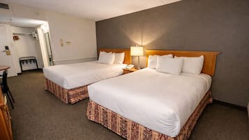 A hotel room with two beds, a desk, and a chair.