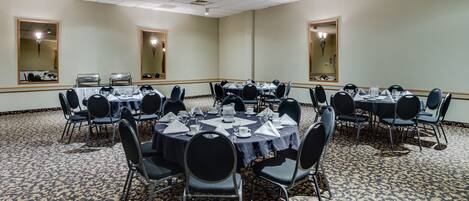 A conference room with round tables, black chairs, and a patterned carpet.
