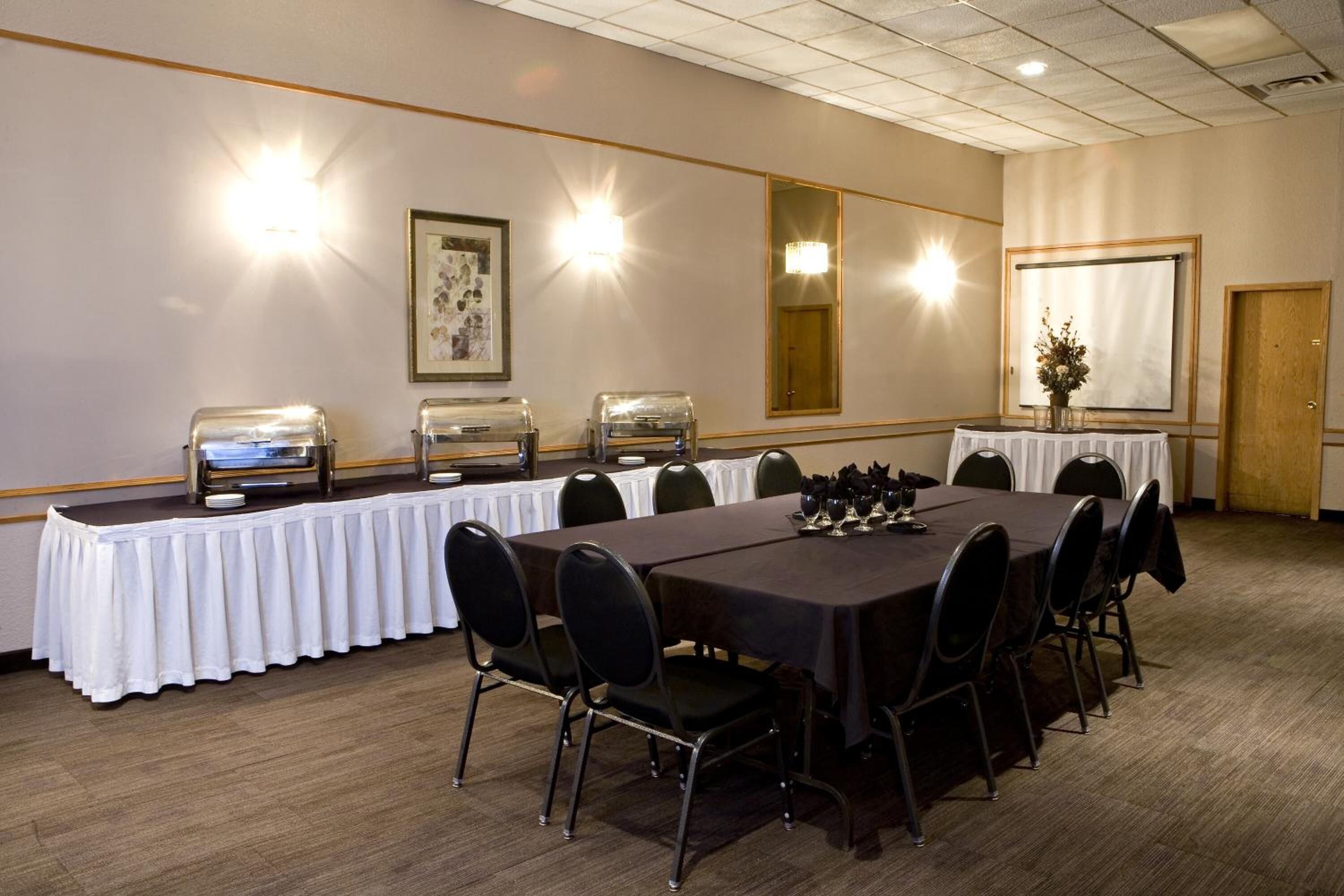 A conference room with a long table, chairs, buffet stations, and wall-mounted lights.