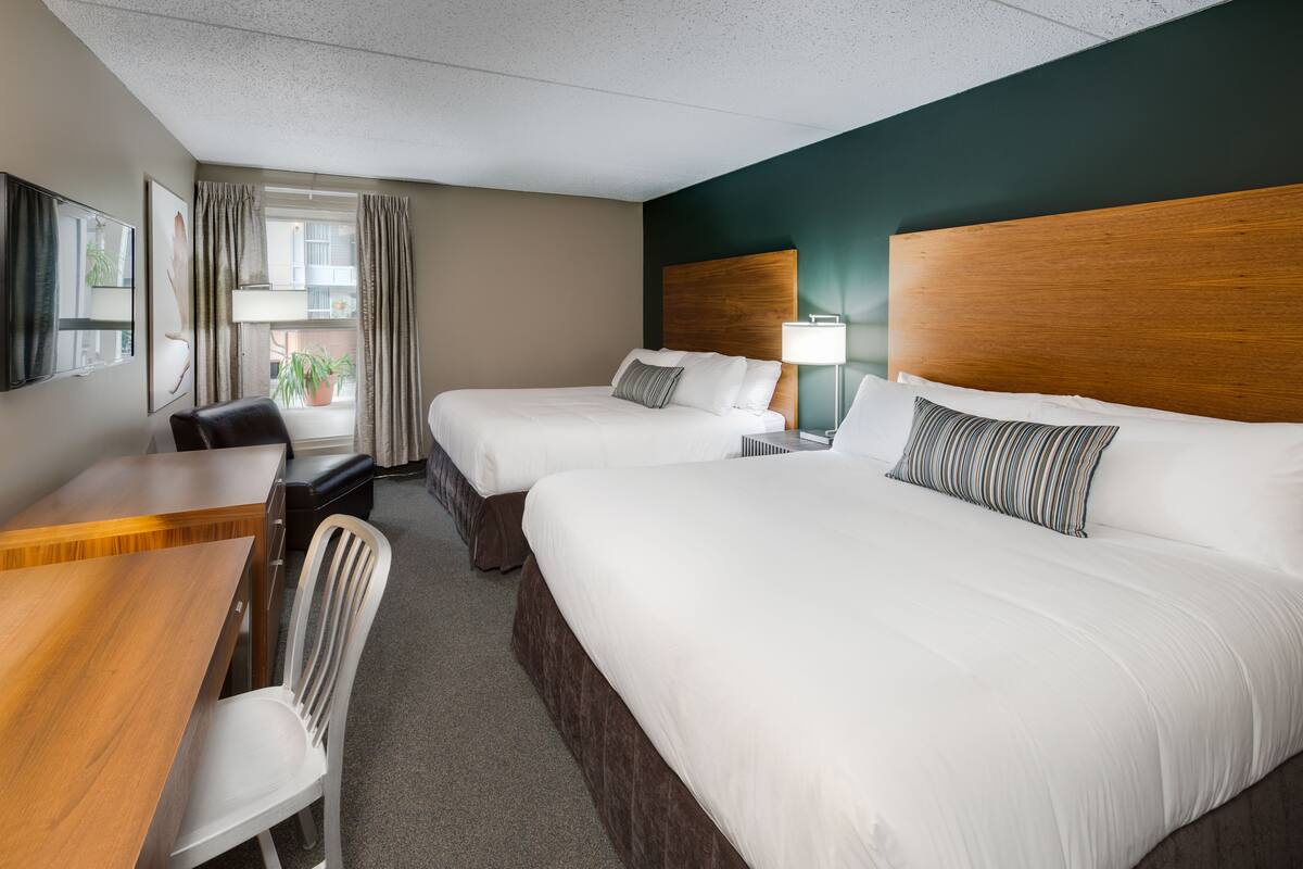Une chambre d’hôtel avec deux lits, un bureau, une chaise et un téléviseur.
