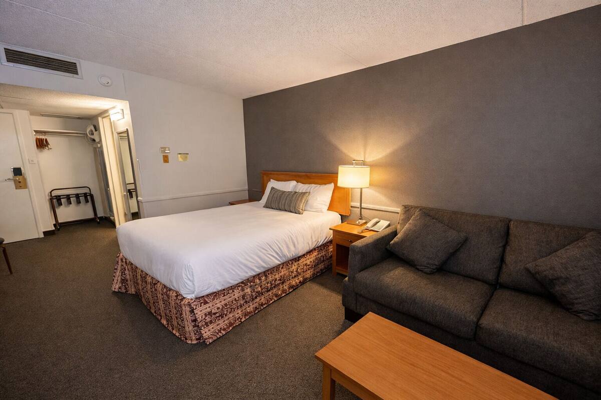 Une chambre d’hôtel comprenant un lit, un canapé, une table de chevet, une lampe et une petite table.