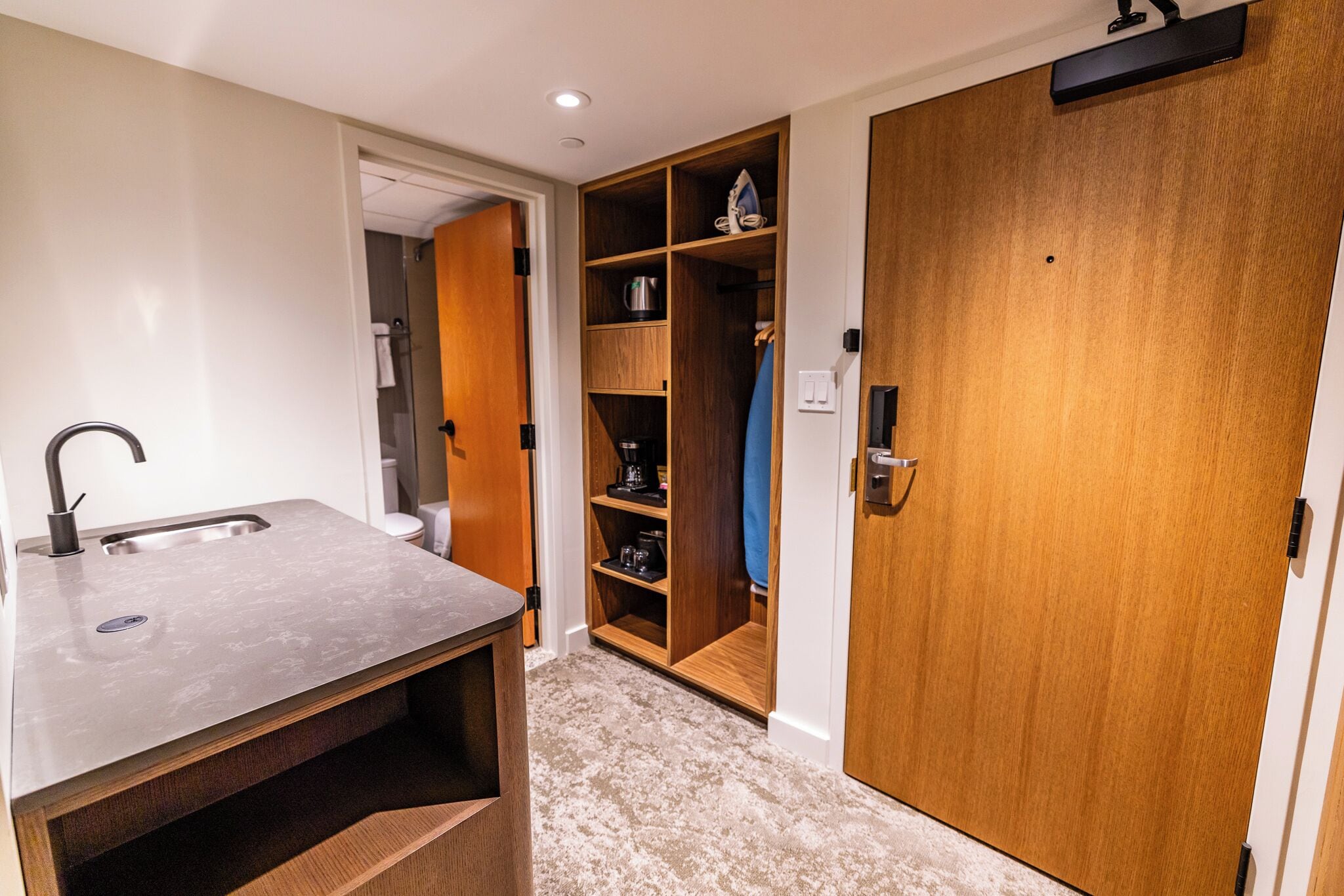 A bathroom with a sink, toilet, and a wooden closet with shelves.