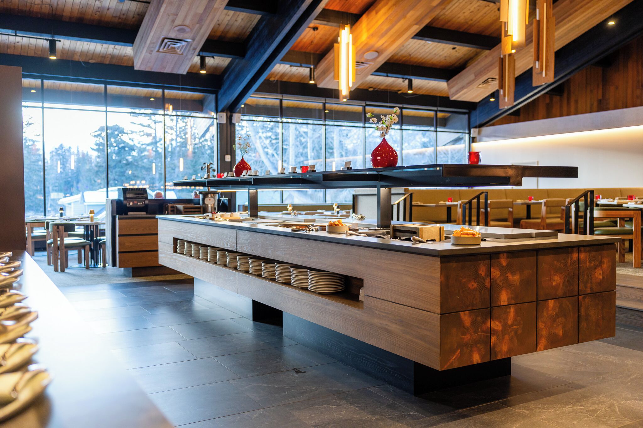 A modern kitchen with a central island, wooden cabinets, and a large window providing a view of the outdoors.