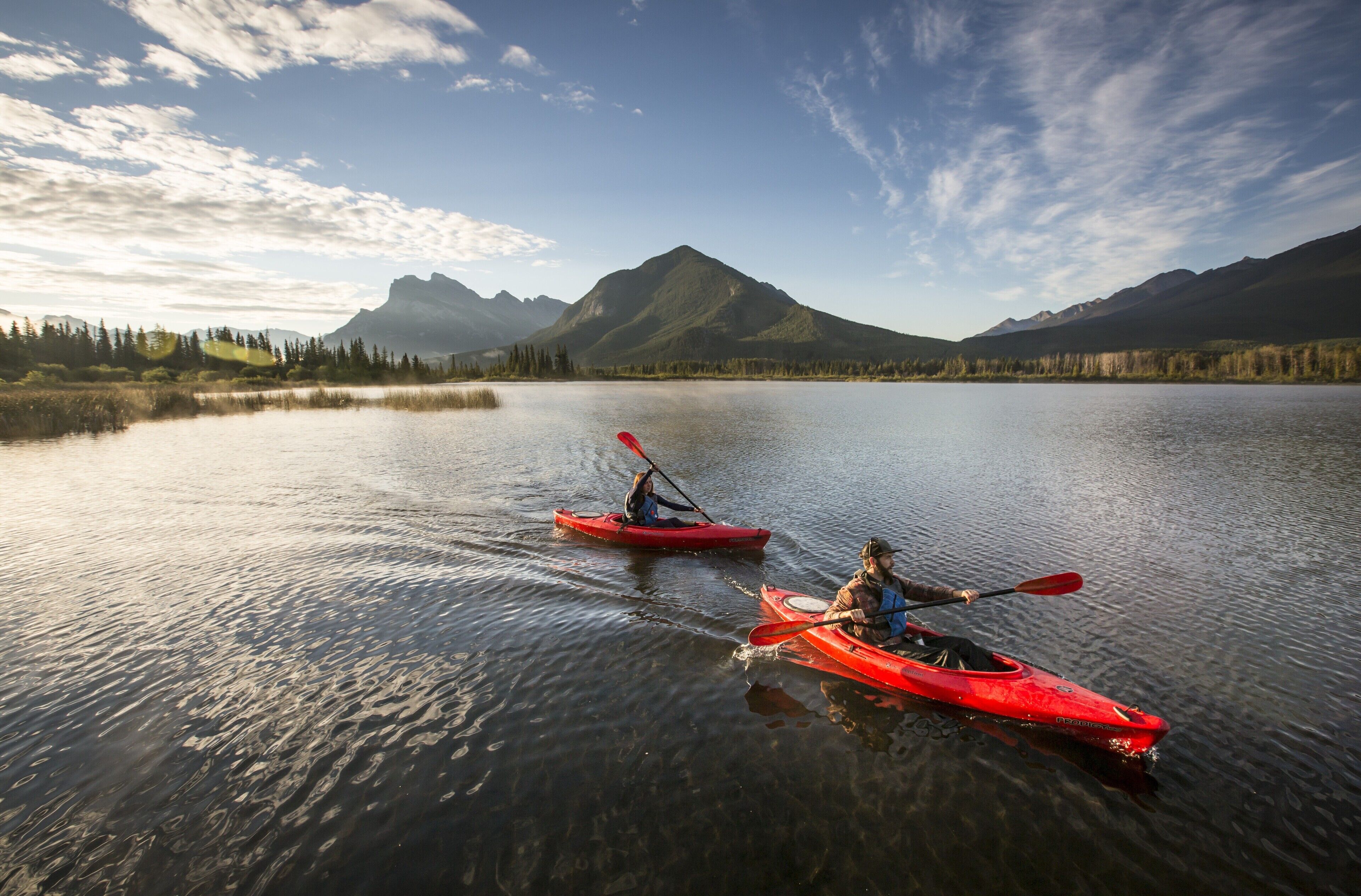 Due kayak su un lago calmo con montagne sullo sfondo.