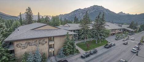A lodge with a prominent sign, multiple parking spaces, and a view of mountains in the background.