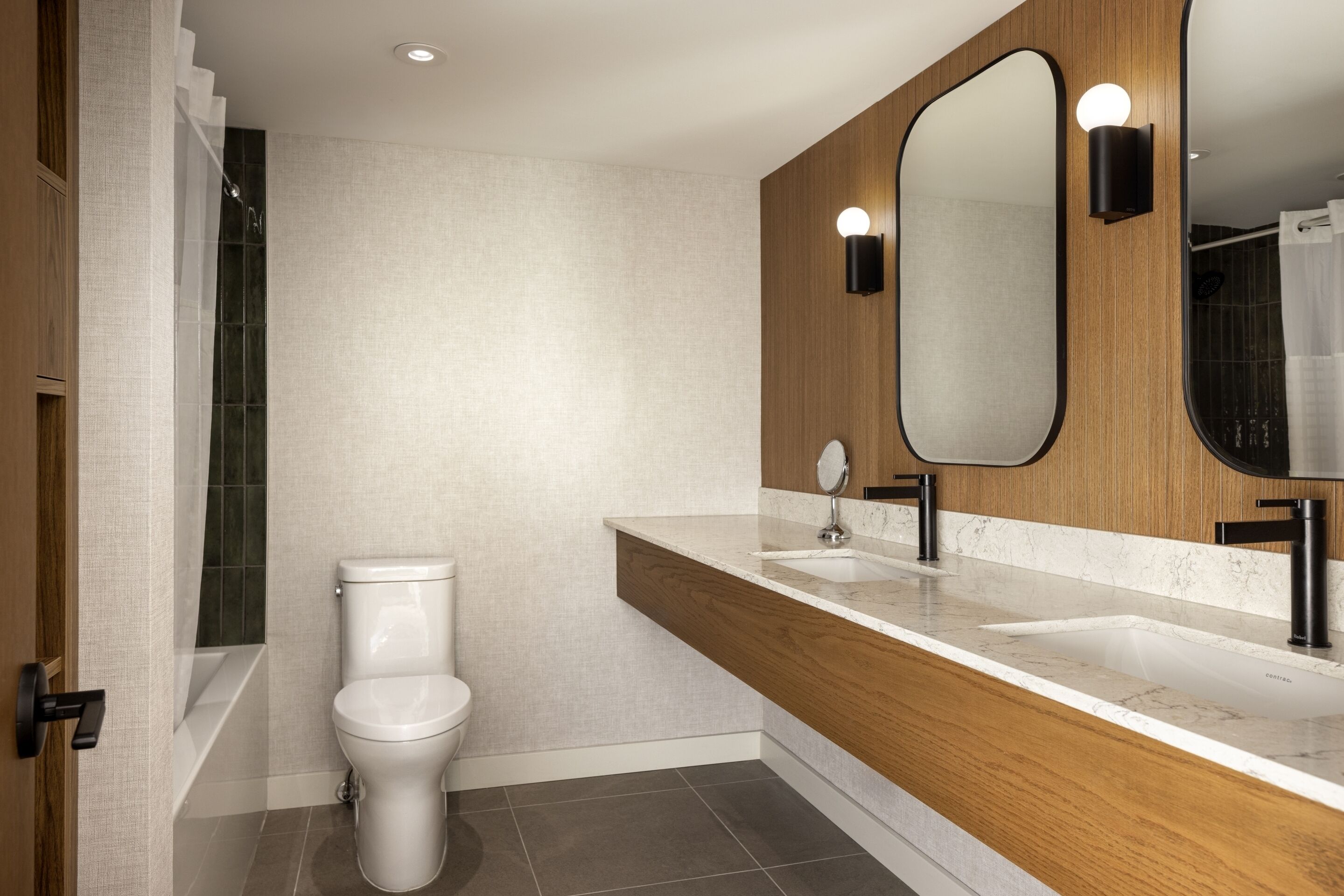 Un baño moderno con inodoro, lavamanos y espejo.