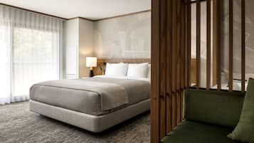 A hotel room with a large bed, a green sofa, a wooden headboard, and a large window with sheer curtains.