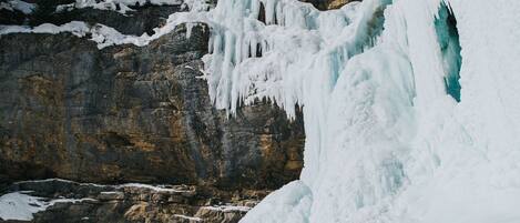 A snowy landscape with a large ice formation and two people standing on a snow-covered slope.