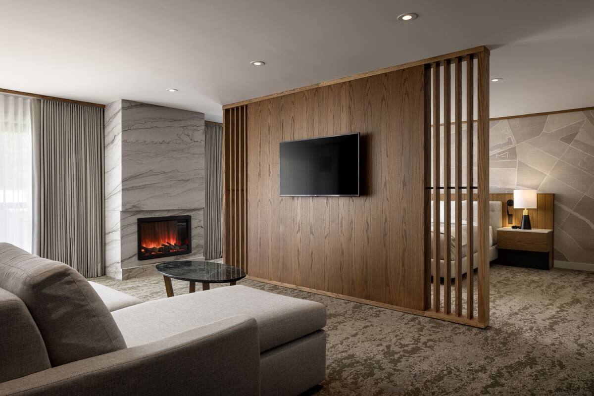 A modern living room with a fireplace, a flat-screen TV, and a wooden partition.