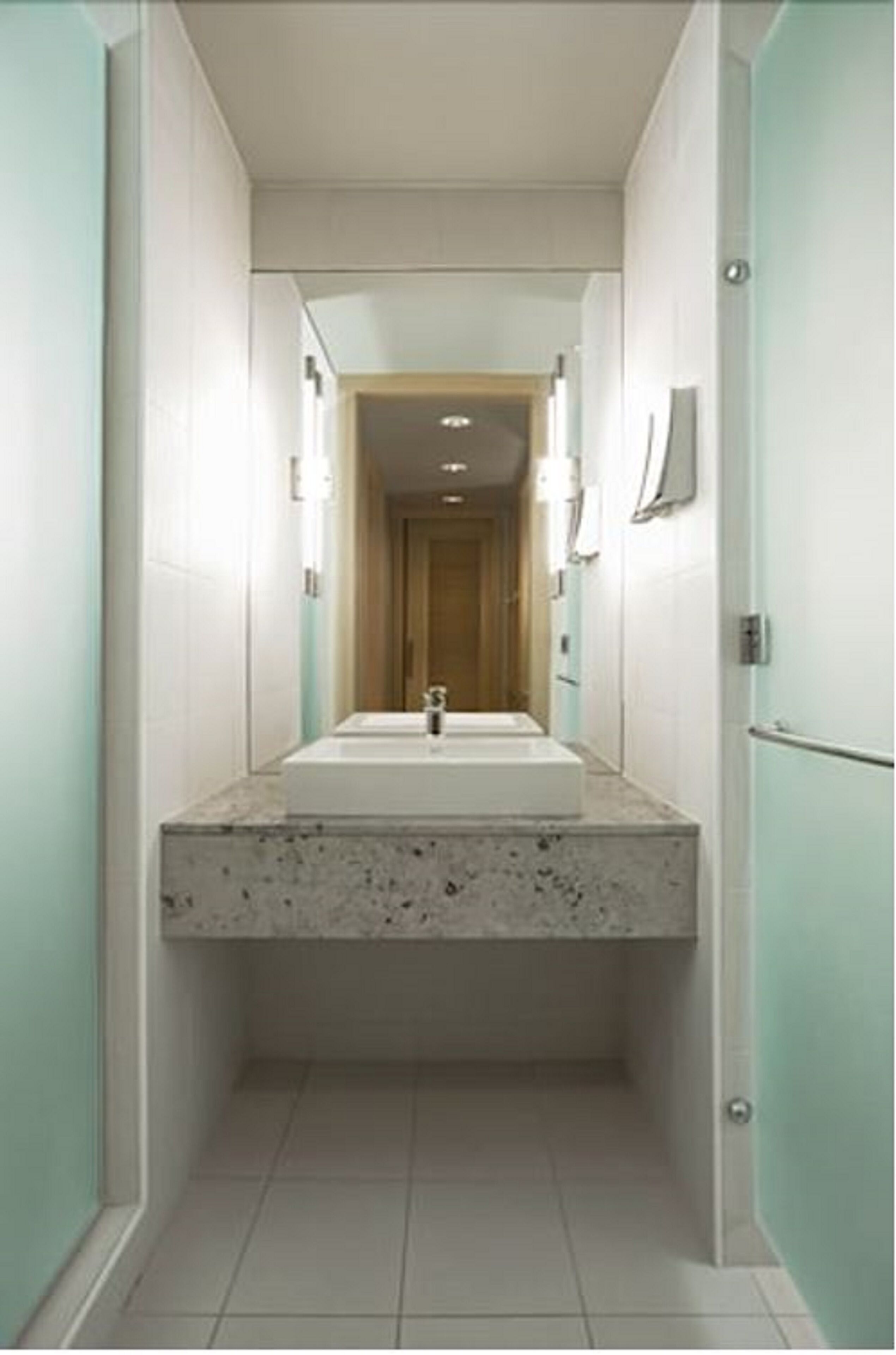 A narrow hallway with a sink and mirror at the end.