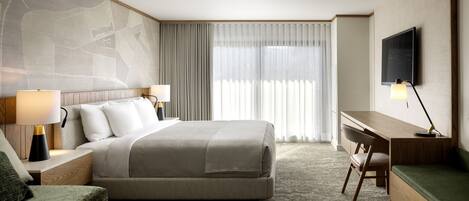 A hotel room with a large bed, a desk, a chair, a TV, and a map on the wall.