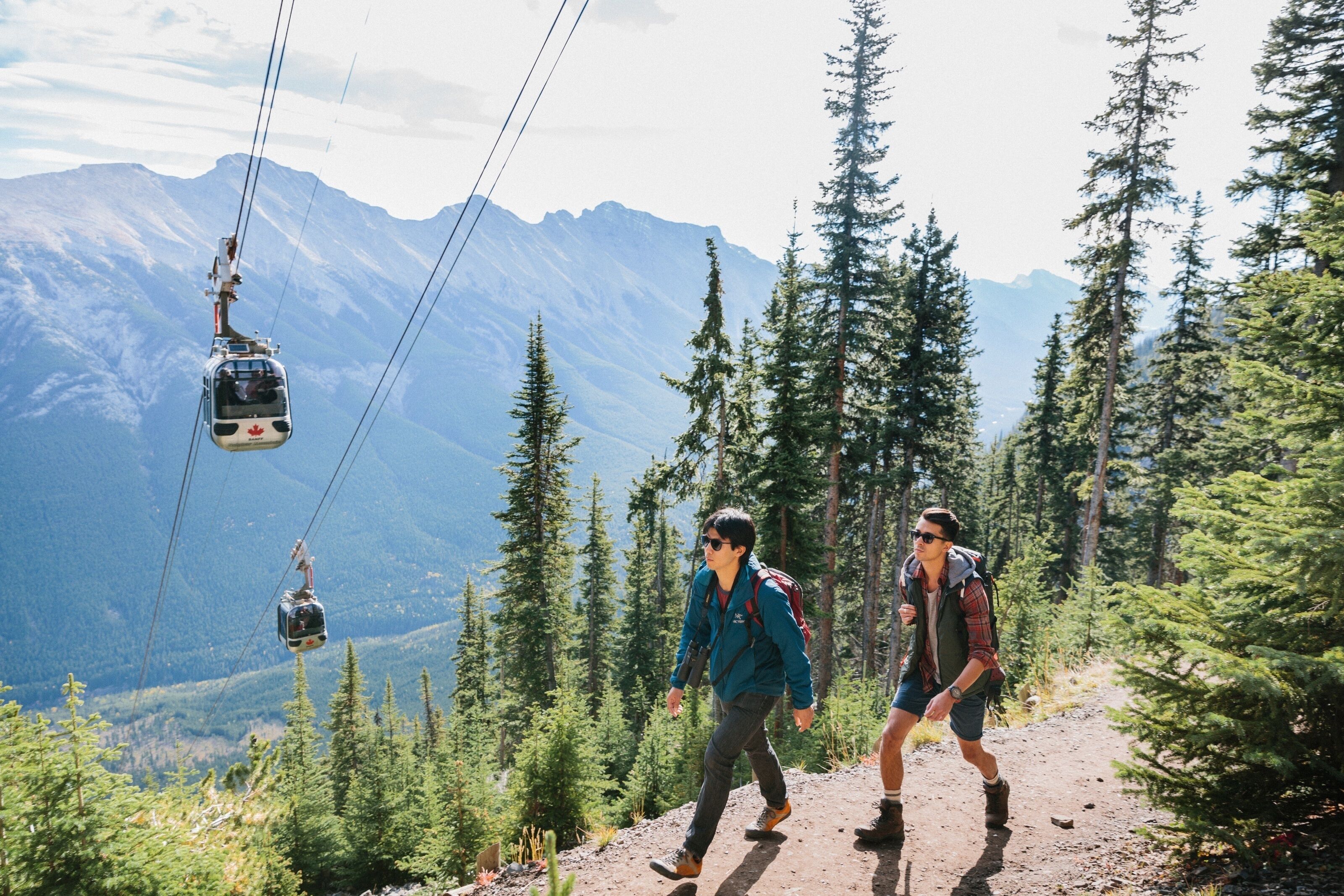 A cable car system in a mountainous area with hikers on a trail.