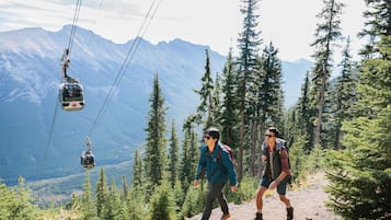 A cable car system in a mountainous area with hikers on a trail.