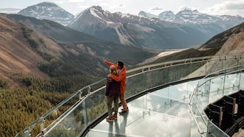 A glass bridge with a panoramic mountain view.