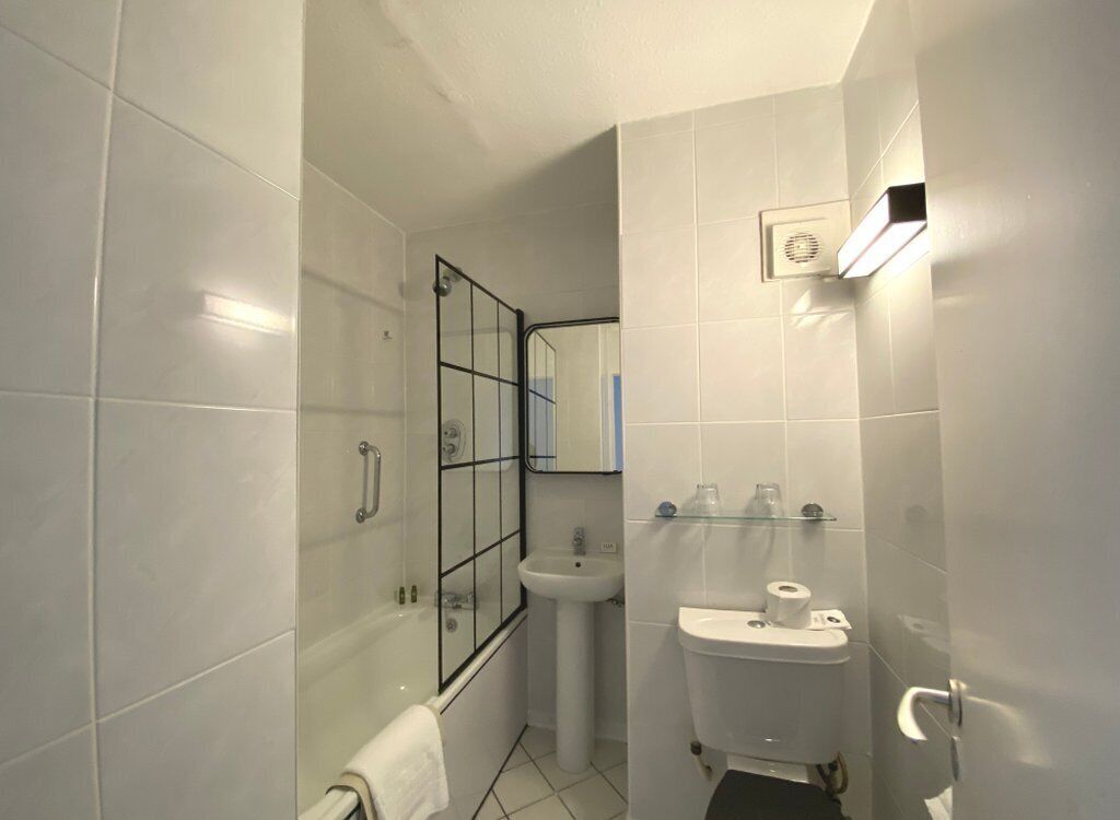A bathroom with a glass shower enclosure, a pedestal sink, and a toilet.