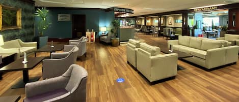 A hotel lobby with seating areas, a restaurant, and a reception desk.