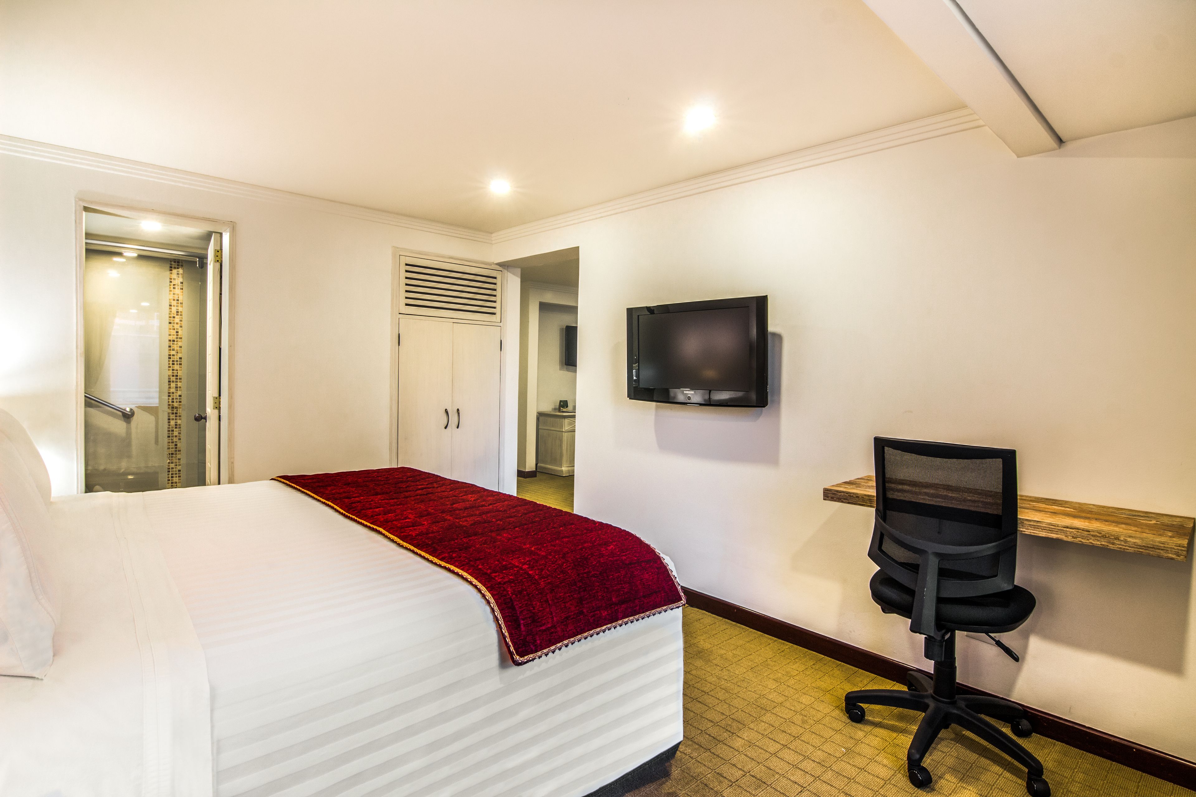 Een hotelkamer met een bed, bureau, stoel, televisie en douche.