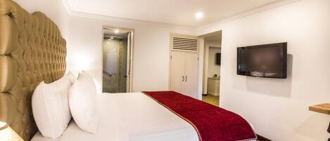 Una habitación de hotel con una cama grande, un televisor en la pared y una puerta que da al baño.